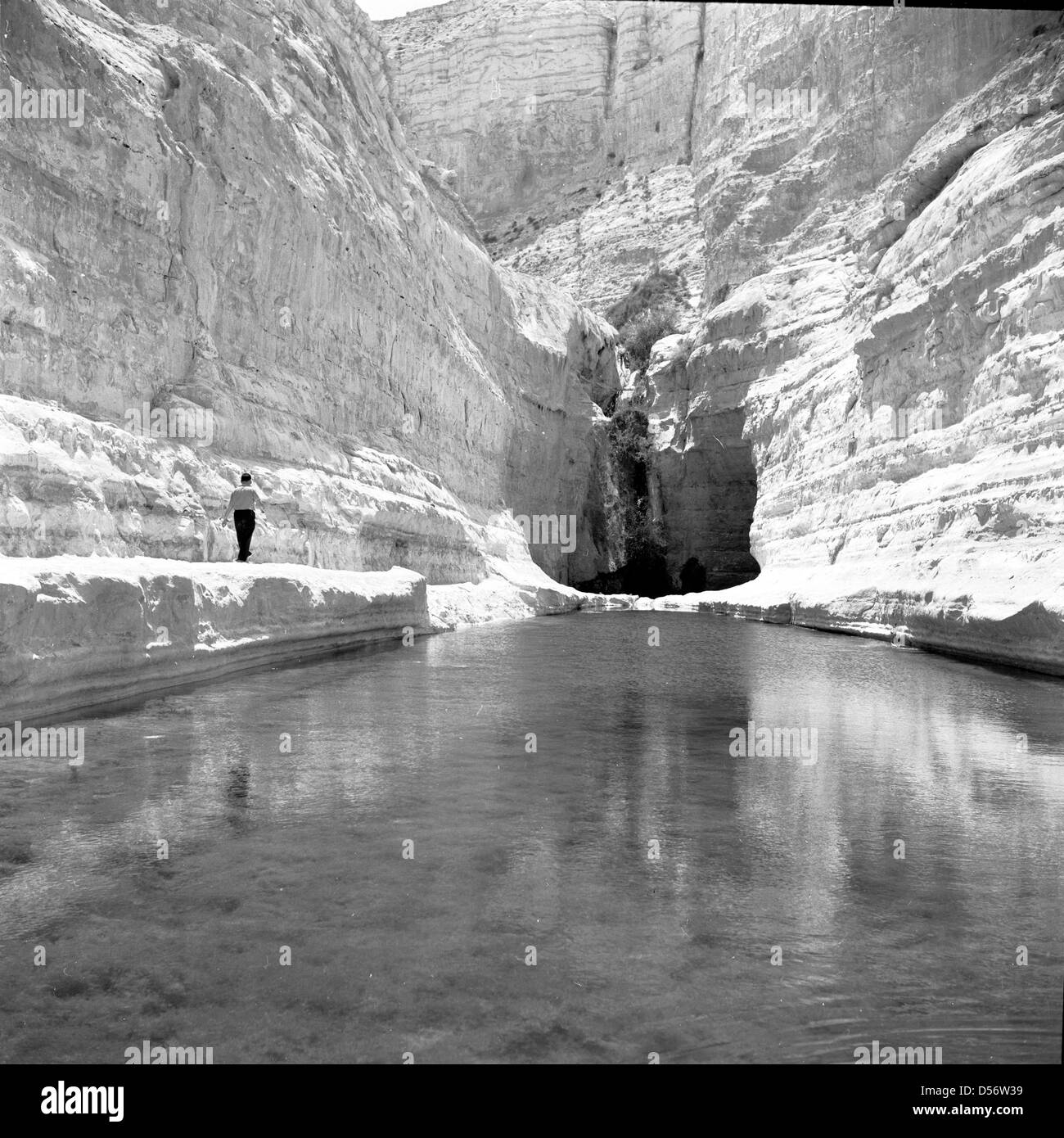 Israele, 1950s. Foto storiche di un uomo a camminare lungo il lato di un ingresso di acqua verso l'entrata di una caverna. Foto Stock