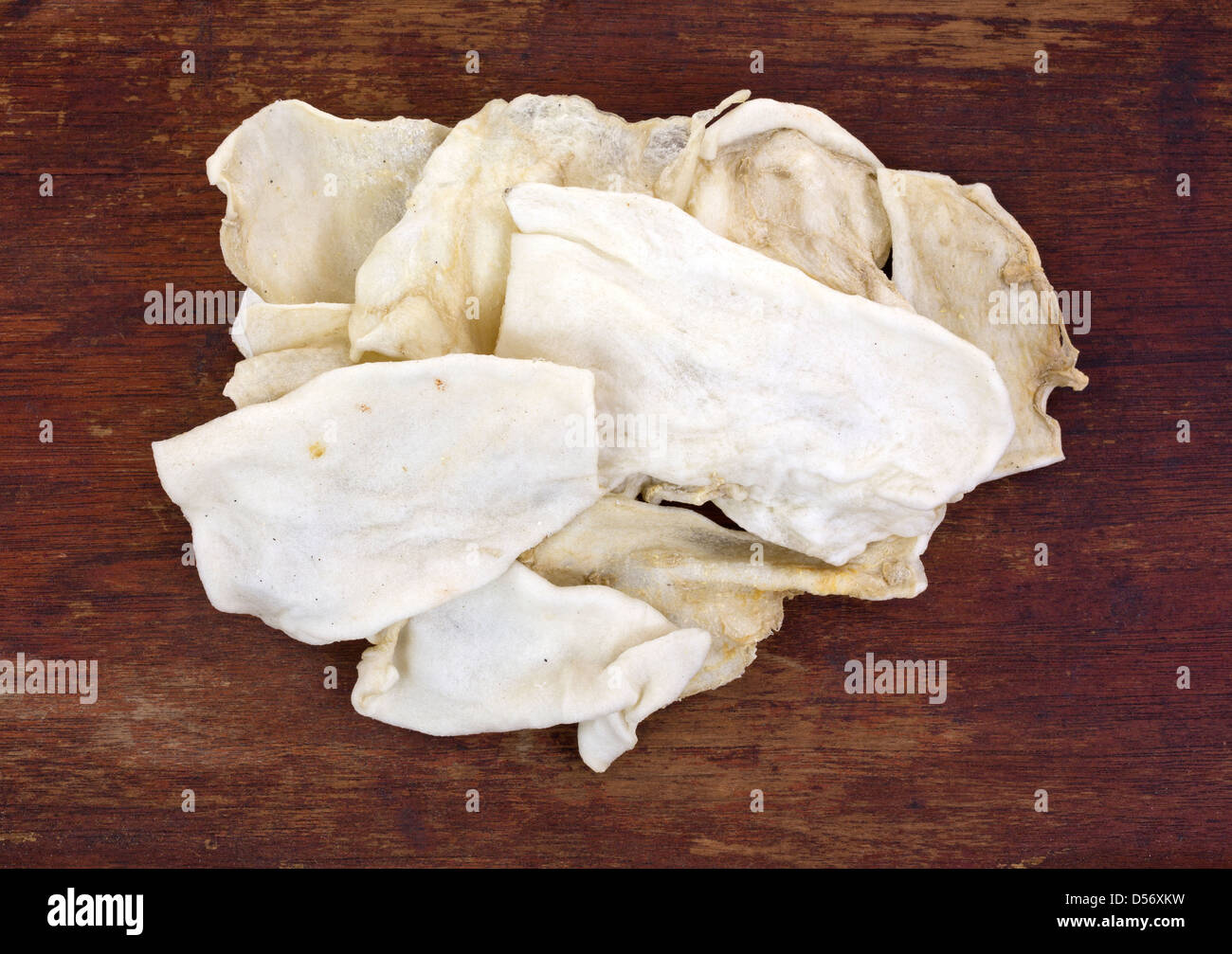 Una piccola pila di cuoio prodotti da masticare per cani su un vecchio usurato superficie di legno. Foto Stock