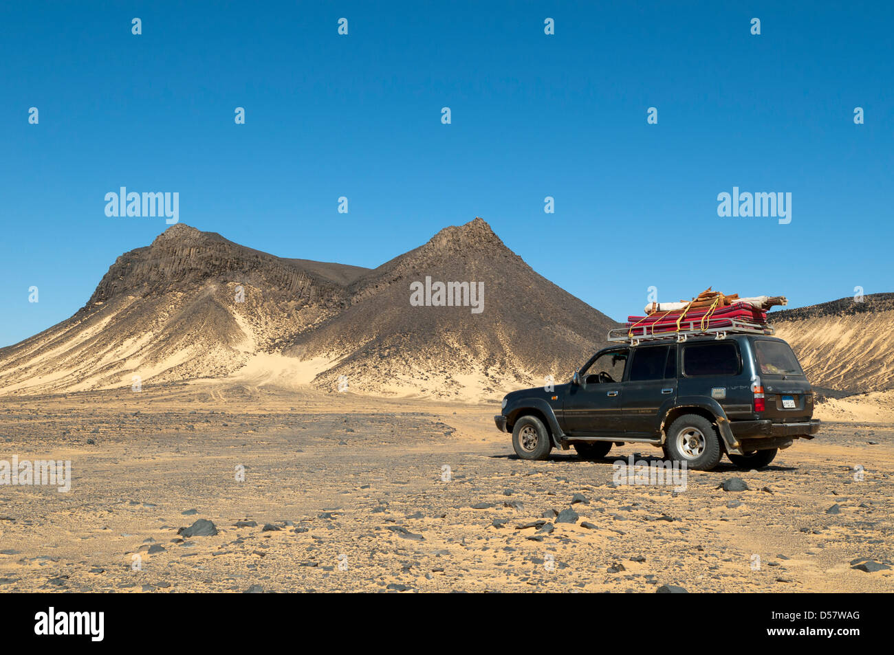 4WD nella parte anteriore del vulcano a forma di montagne del Deserto nero, Egitto Foto Stock