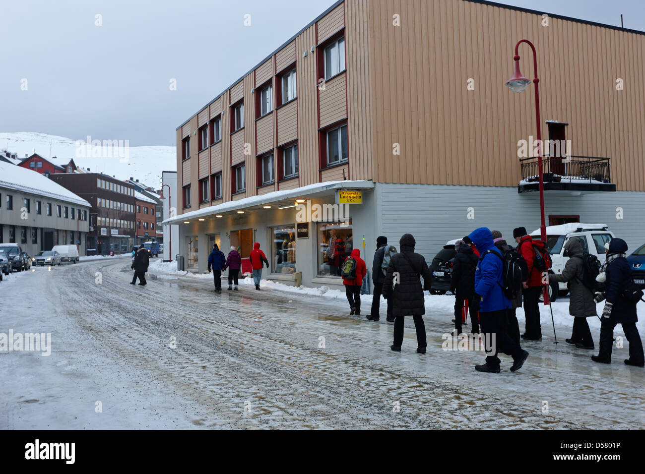 La gente camminare lungo coperto di ghiaccio storgata strada principale dello shopping di Honningsvag finnmark Norvegia europa Foto Stock