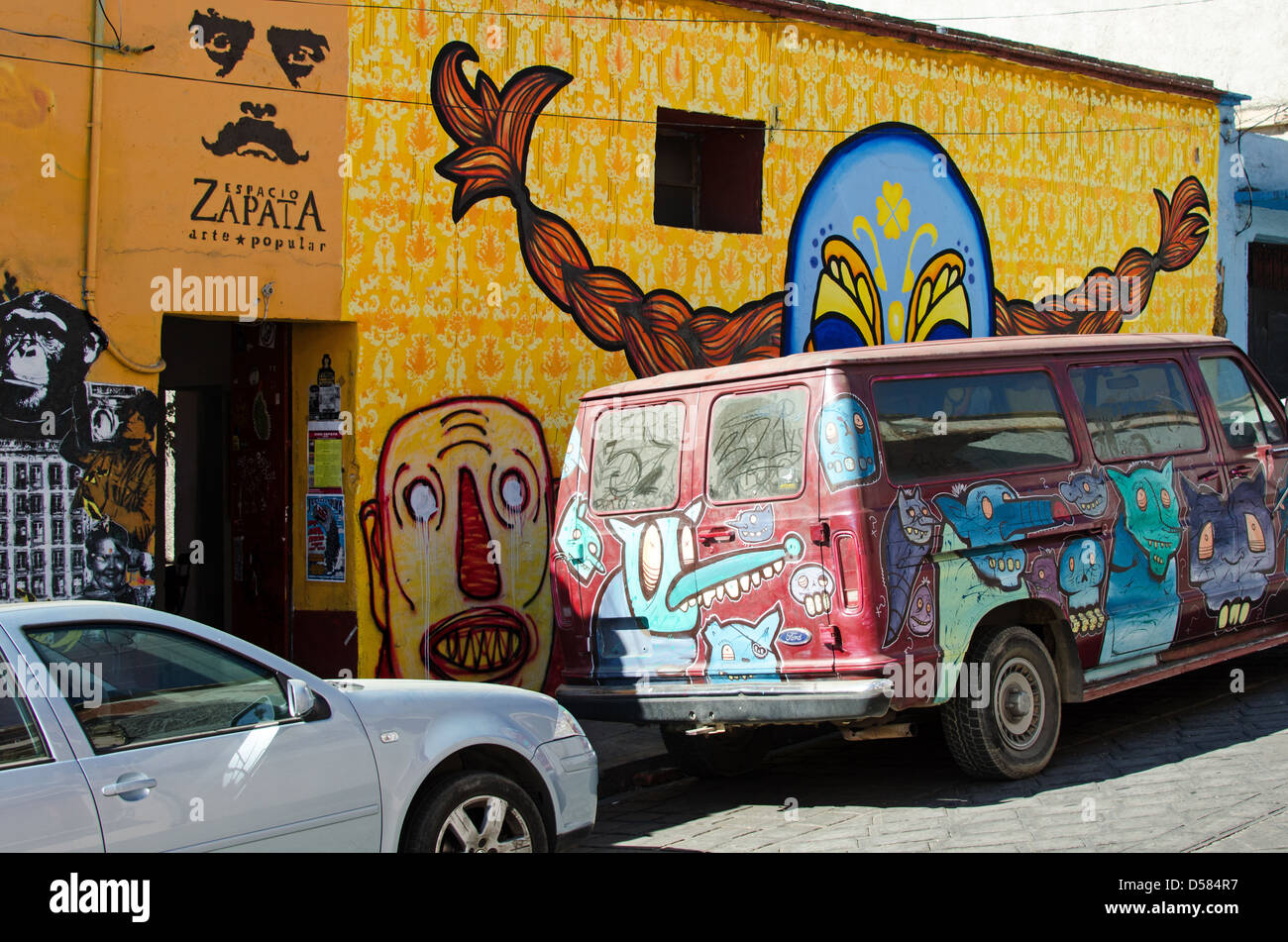 Van dipinte dall'artista SCOM parcheggiata di fronte un murale da Kollektivet Livet fuori Espacio Zapata gallery; Oaxaca, Messico. Foto Stock