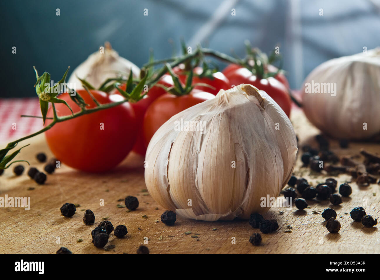 L'aglio, il pomodoro ciliegino e pepe sementi sul piatto di legno sul tavolo da cucina. cibo sano sfondo. Foto Stock