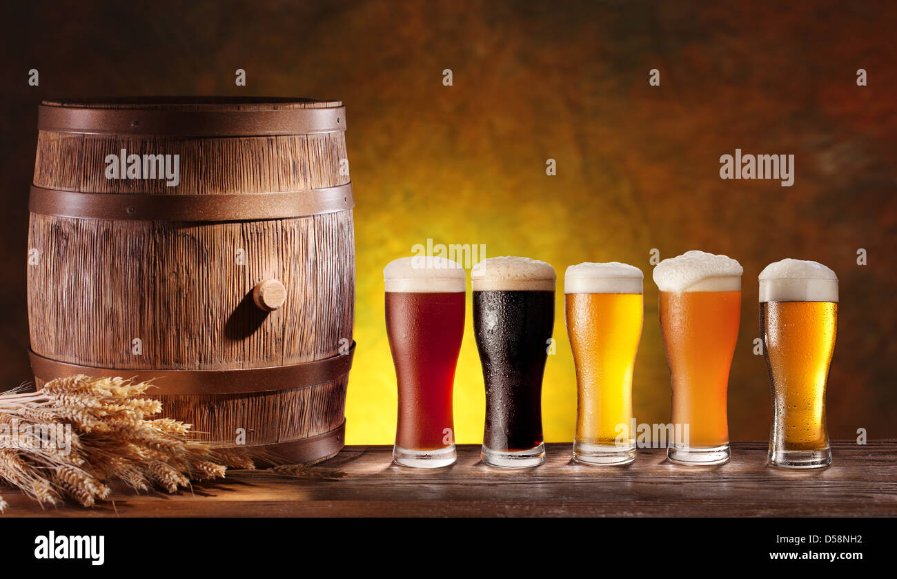 Assortimento di bicchieri da birra con un barile di legno. Sfondo - giallo scuro gradiente. Foto Stock