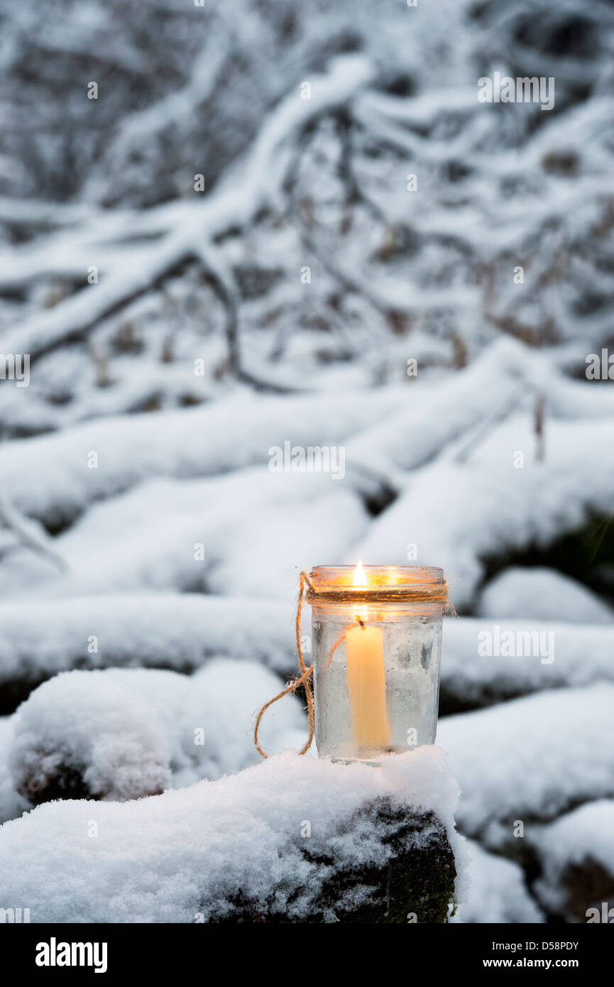 Candela di natale in un vasetto di vetro in una coperta di neve il legno Foto Stock