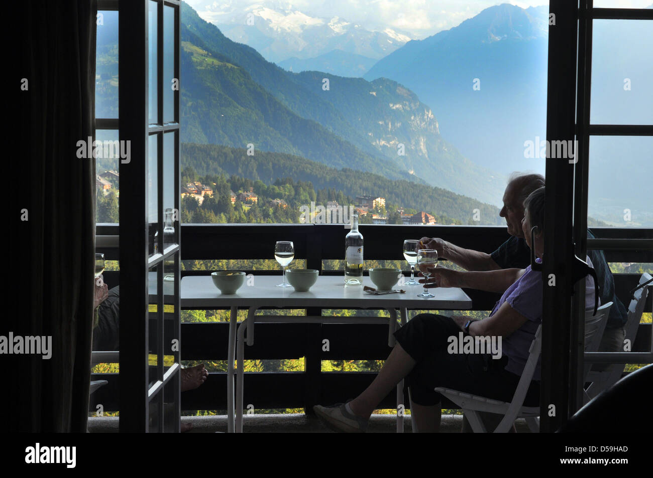 Una coppia in pensione potrete gustare un bicchiere di vino sul loro Chalet Svizzero balcone, Svizzera. Foto Stock