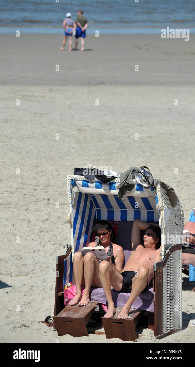Urlauber liegen am Freitag (25.06.2010) auf der Insel Borkum in einem Strandkorb und sonnen sich bei herrlichem Wetter mit angenehmen Temperaturen. Auch in den nŠchsten Tagen ist mit Sonne zu rechnen. Foto: Carmen Jaspersen dpa/L  Foto Stock