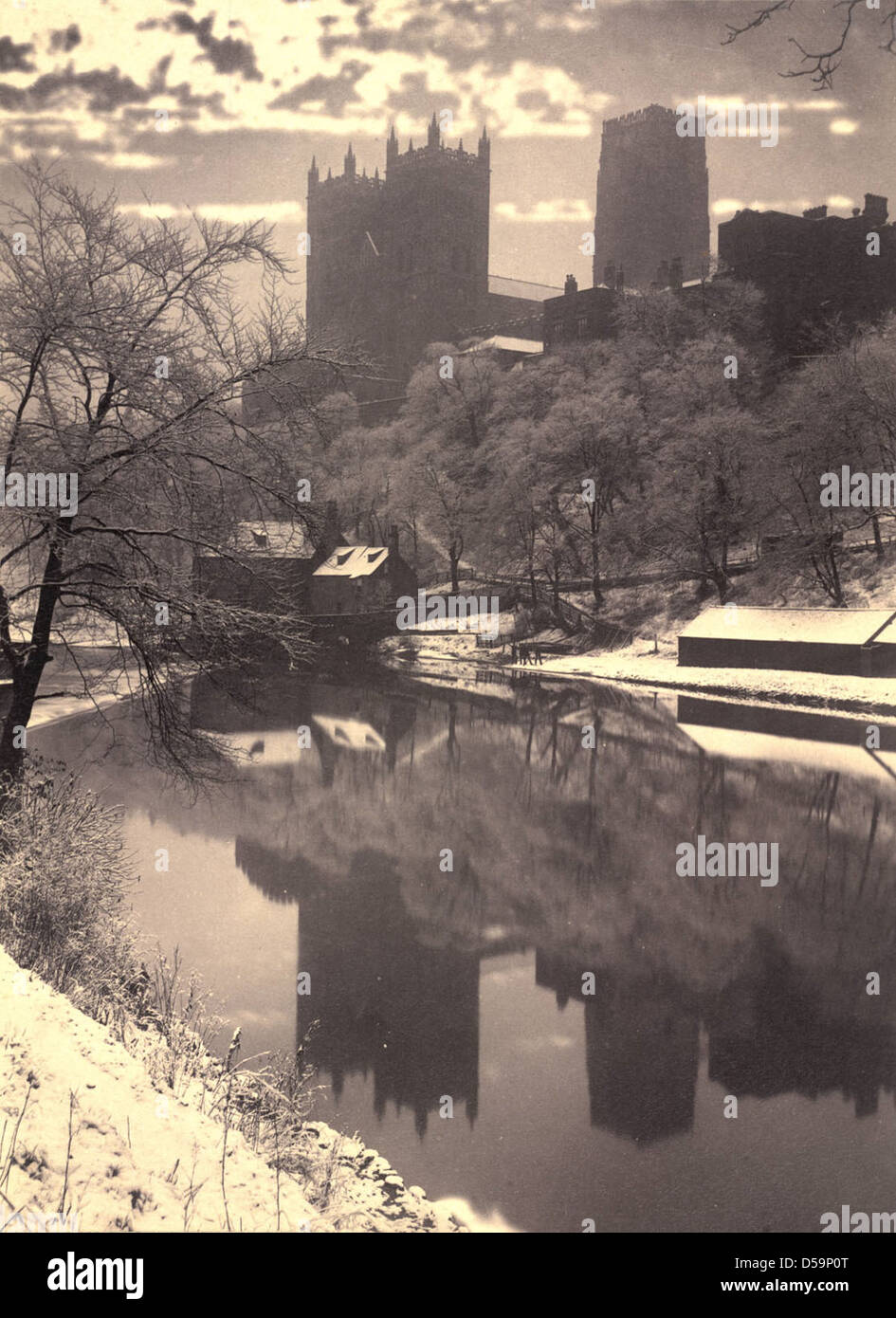 Una vista panoramica della Cattedrale di Durham, situata sulle rive del fiume Wear nella Contea di Durham, Inghilterra, catturata durante l'inverno. La struttura torreggiante della cattedrale si riflette nel fiume, circondato dalla neve. Foto Stock