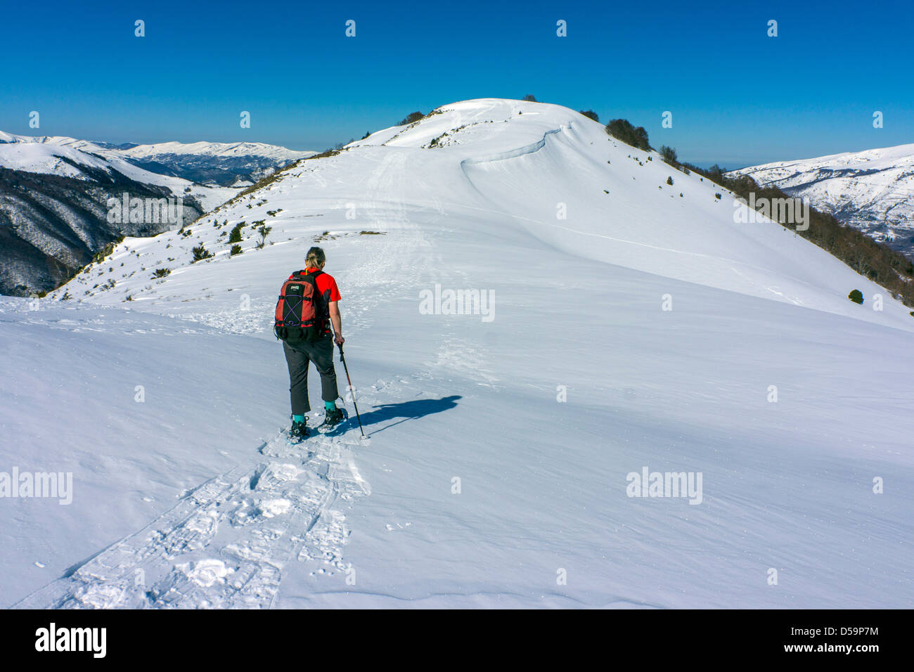 Femmina in rosso con le racchette da neve sul pendio di neve, Plateau de Beille, Pirenei francesi Foto Stock