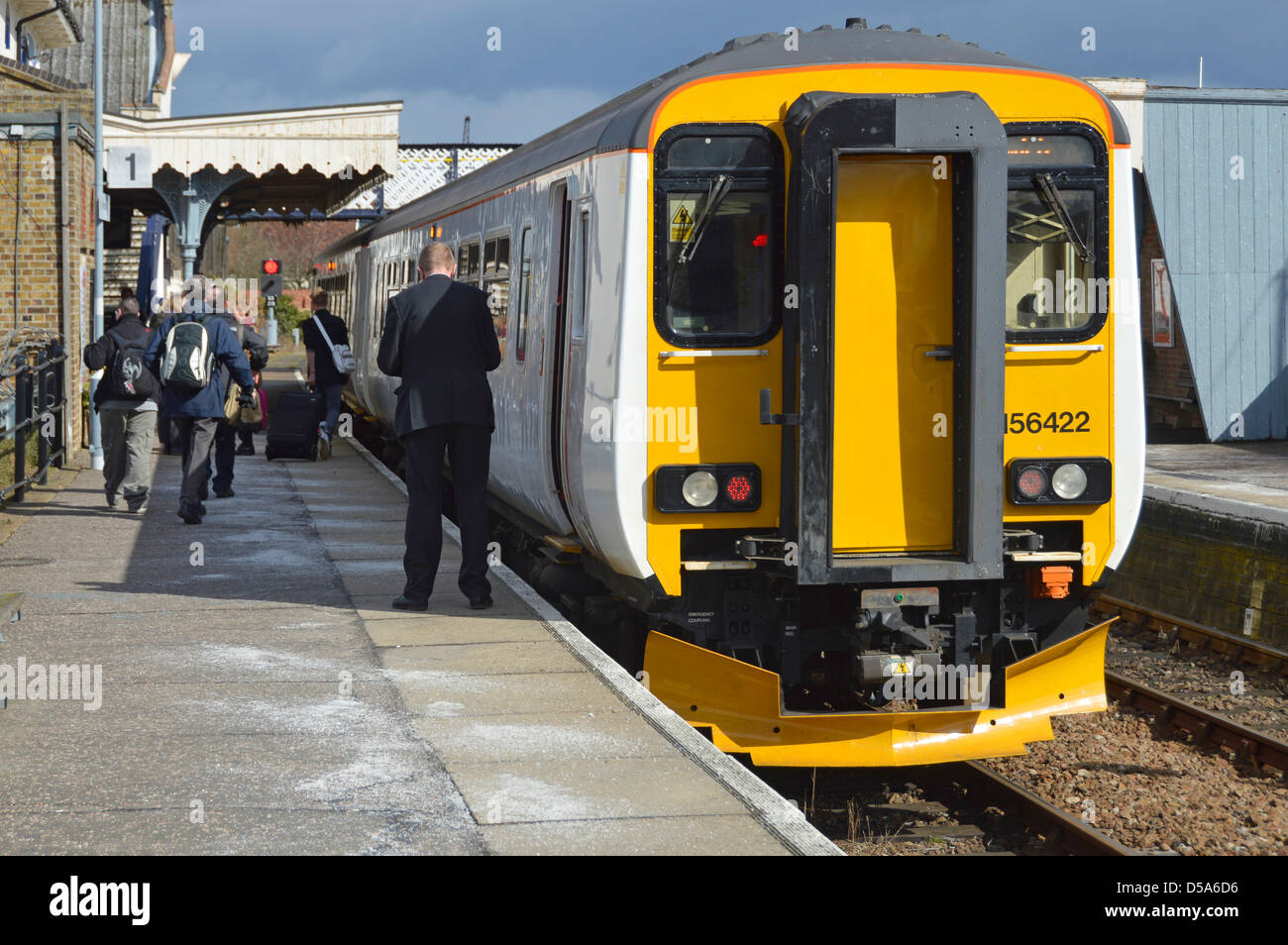 I viaggiatori lasciando una maggiore Anglia treno a Woodbridge stazione ferroviaria nota bianco granuli di sbrinamento diffusione sulla piattaforma Foto Stock
