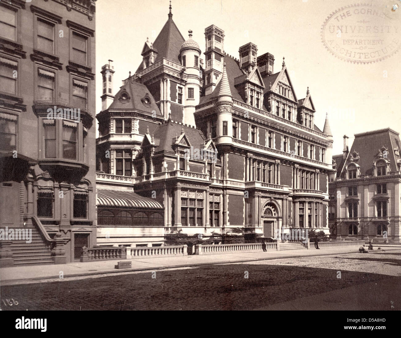 Un'immagine della residenza Cornelius Vanderbilt II a Manhattan, che mostra le sue caratteristiche architettoniche distintive come portali ad arco e marciapiedi in ciottoli, sullo sfondo delle vedute della città. Foto Stock