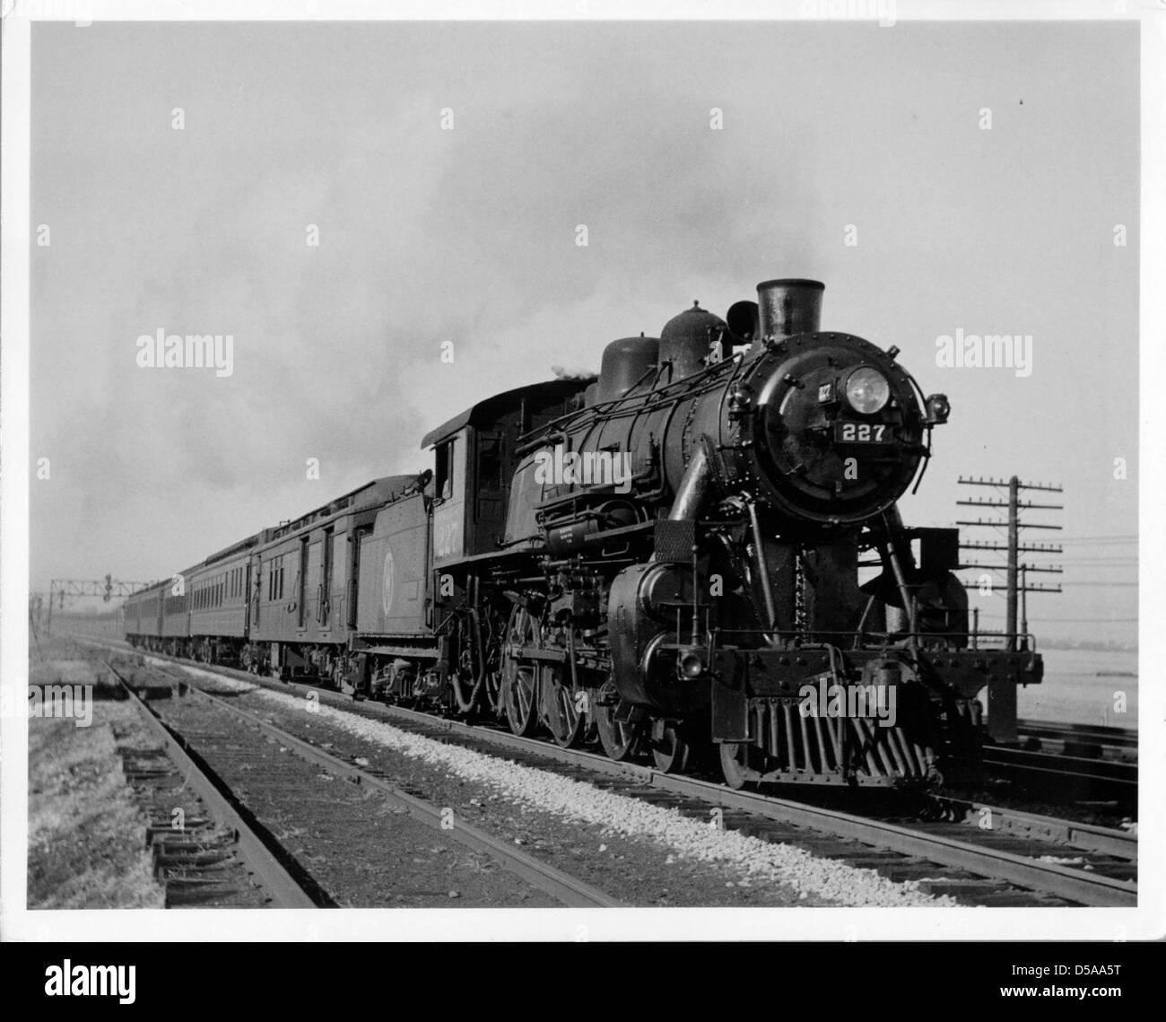La loco #227 è una locomotiva a vapore raffigurata in questa immagine storica, accompagnata da un treno passeggeri. La fotografia cattura un sistema ferroviario dell'inizio del XX secolo, che mostra il ruolo significativo dei treni a vapore nella storia dei trasporti. Foto Stock