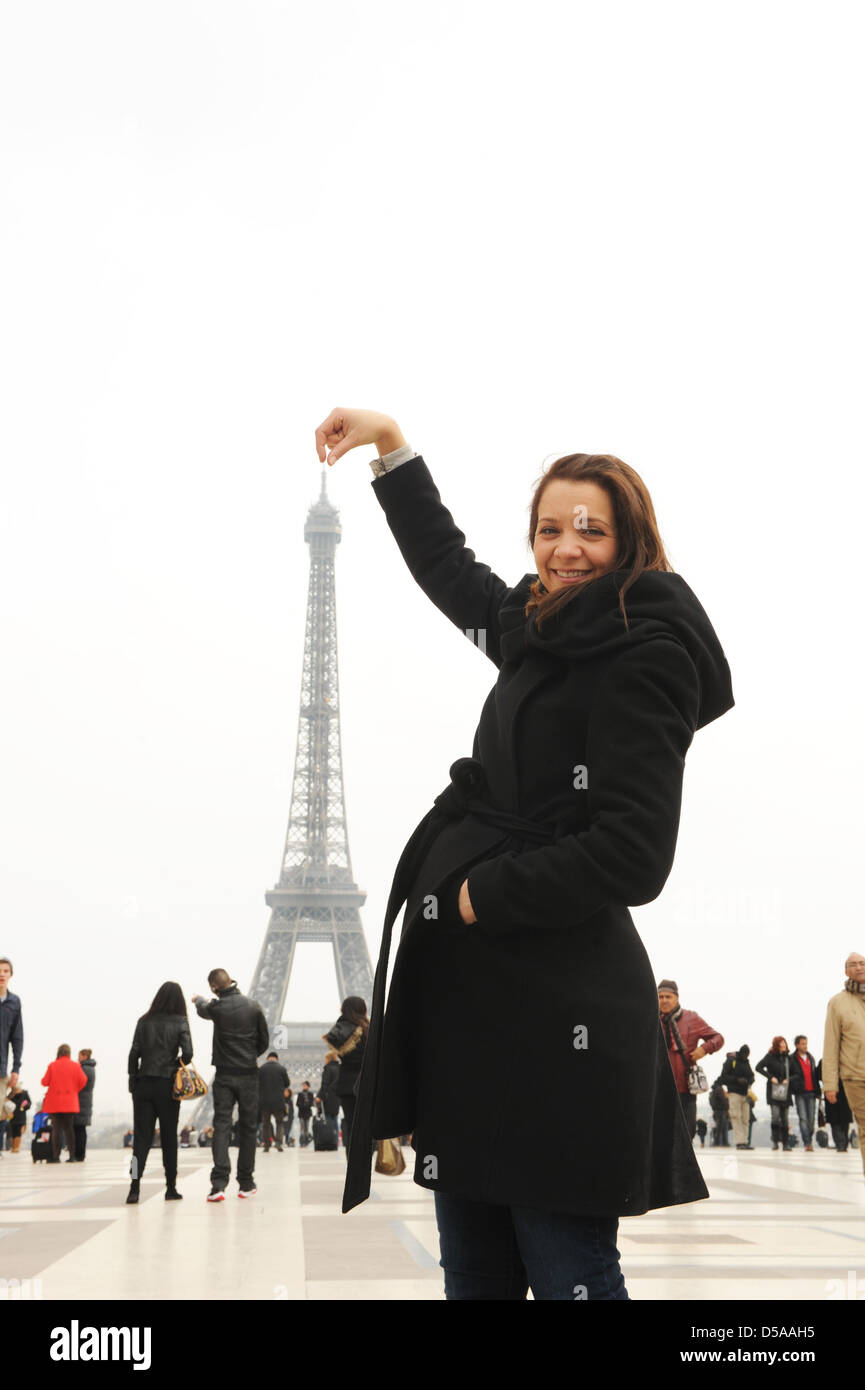 Giovane donna e Torre Eiffel Parigi Francia. Francese punto di riferimento turistico visitatori turismo divertirsi Foto Stock