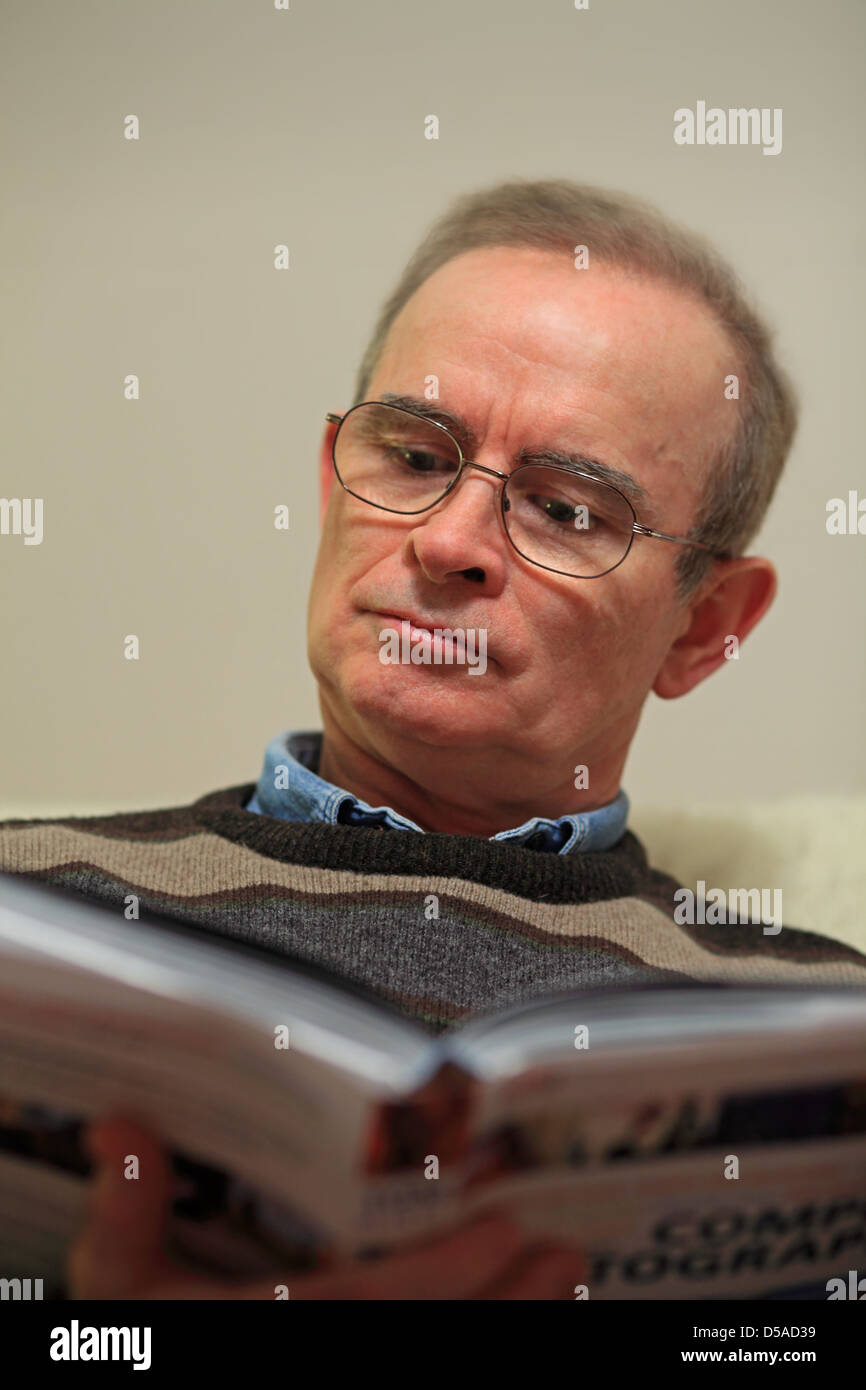 Uomo maturo la lettura di libro a casa in Irlanda Foto Stock