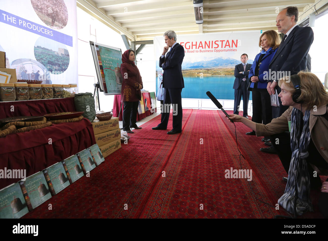 Kamila ha Siddiqi, proprietario di Naweyan Nawed Ltd, spiega il successo della sua strategia di esportazione per la frutta secca e i dadi per il Segretario di Stato americano John Kerry durante una donna vetrine aziendali presso l'Ambasciata USA Marzo 26, 2013 a Kabul, Afghanistan. Foto Stock