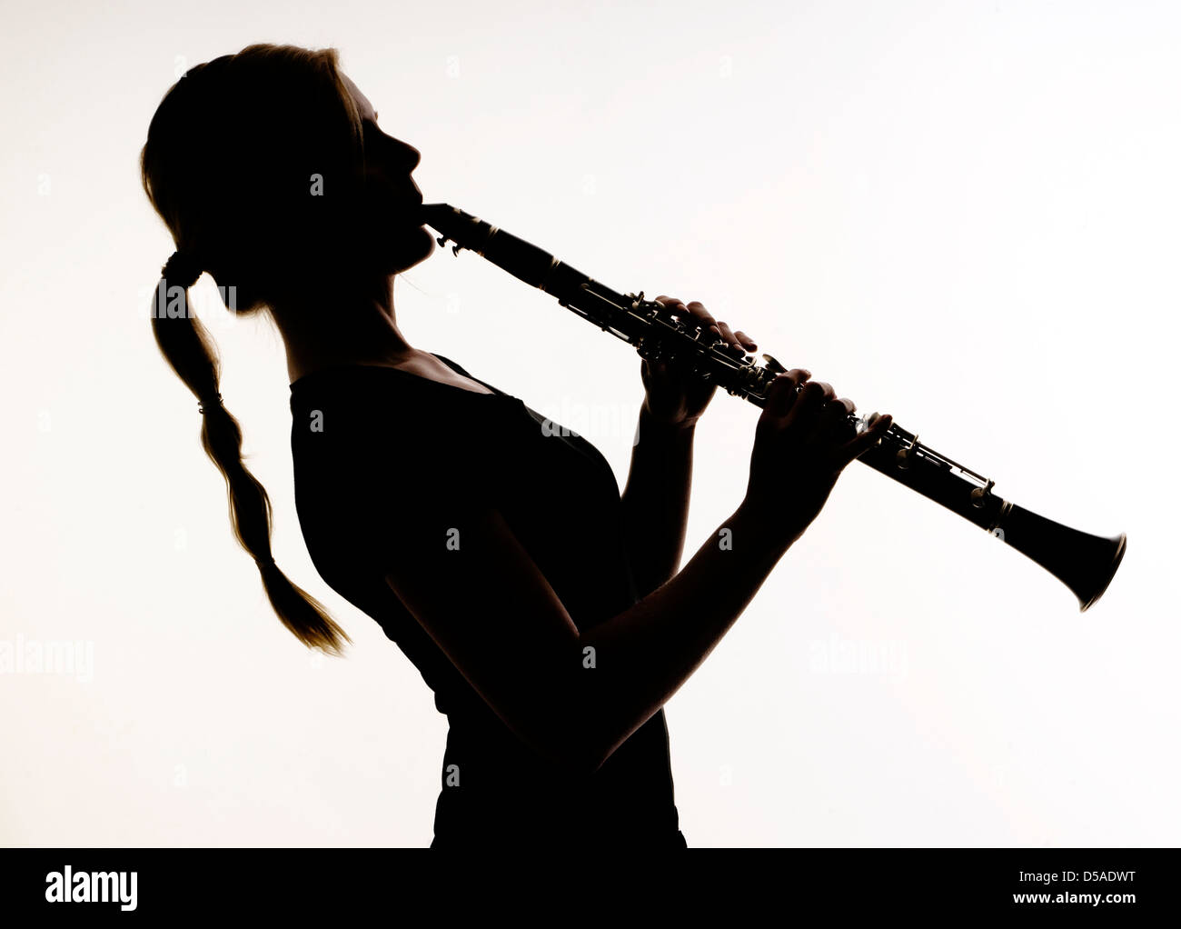 Femmina pratiche musicista la sua tecnica di legni su un clarinetto fotografato in silhouette Foto Stock