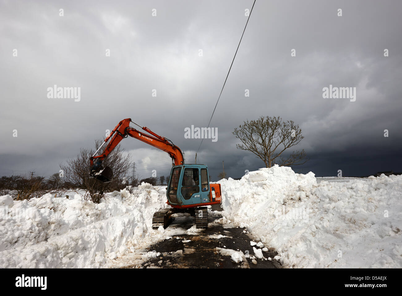 trattore sgombero corsia paese con forti derive della contea di neve antrim irlanda del nord regno unito per raggiungere la comunità rurale tagliata fuori Foto Stock