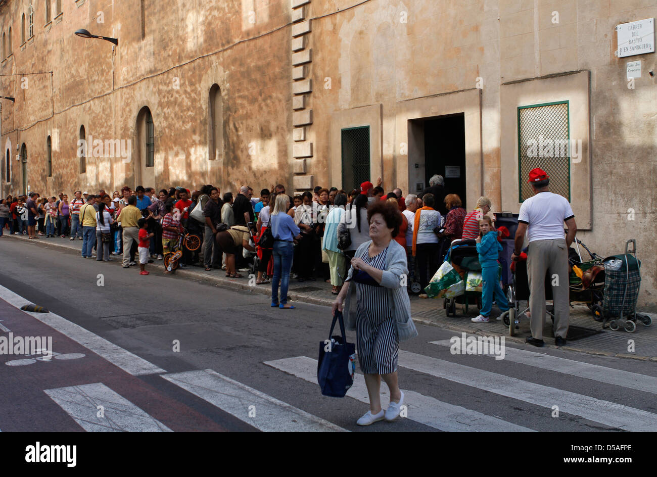 Decine di persone in attesa in una coda di un centro di carità per ricevere settimanalmente un sacchetto di prima necessita di cibo e vestiti. Foto Stock