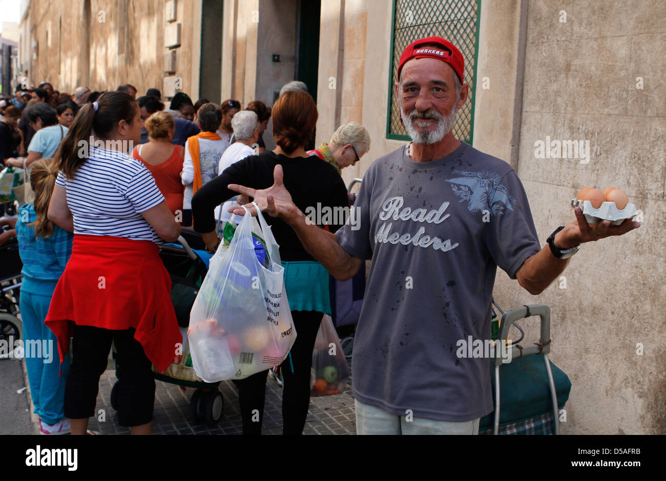Decine di persone in attesa in una coda di un centro di carità per ricevere settimanalmente un sacchetto di prima necessita di cibo e vestiti. Foto Stock