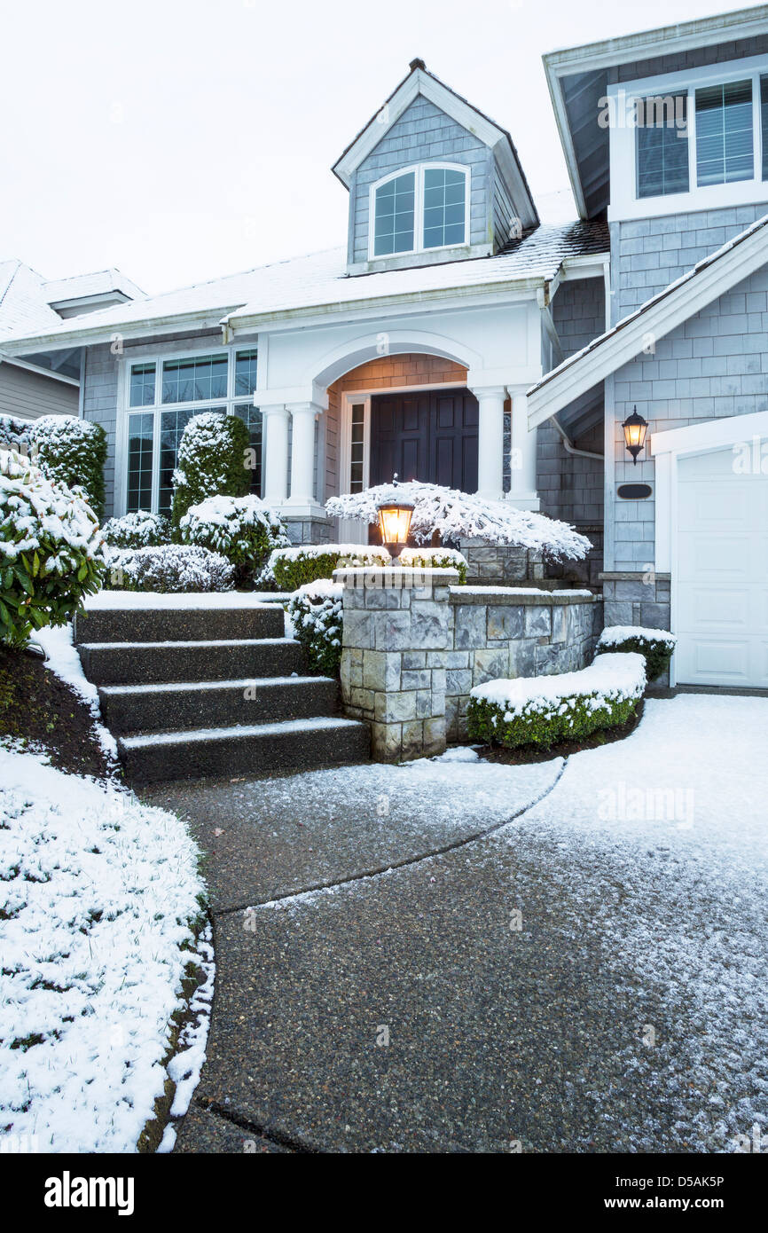 Foto verticale del lato passeggiata che conduce alla casa suburbana con neve sul terreno Foto Stock