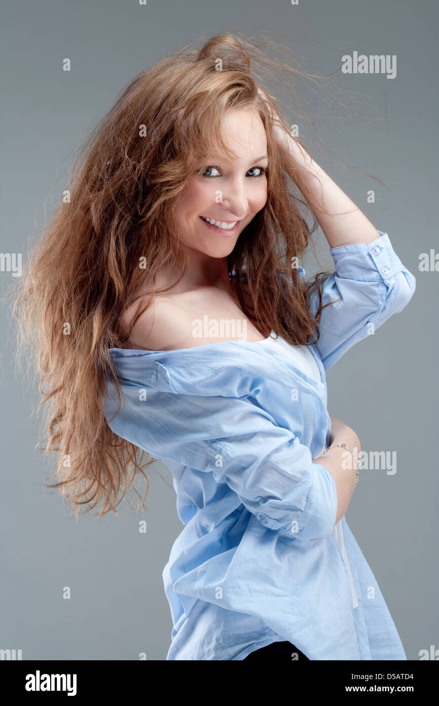 Ritratto di una giovane bella donna con capelli castani sorridendo - isolato su grigio Foto Stock