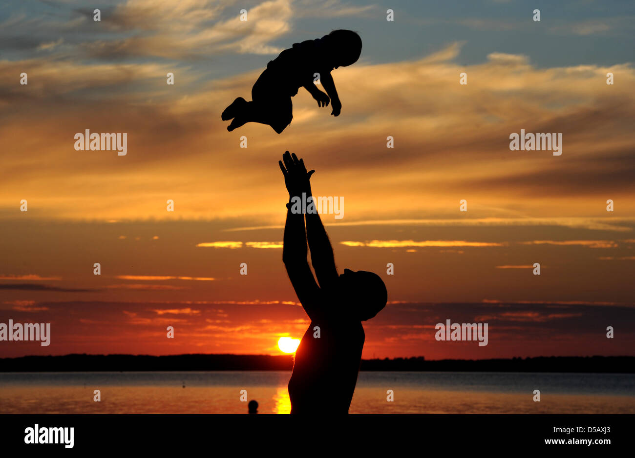 Un padre gioca con il suo bambino durante un fantastico tramonto vicino Noer, Germania, 19 luglio 2010. Foto: Julian Stratenschulte Foto Stock