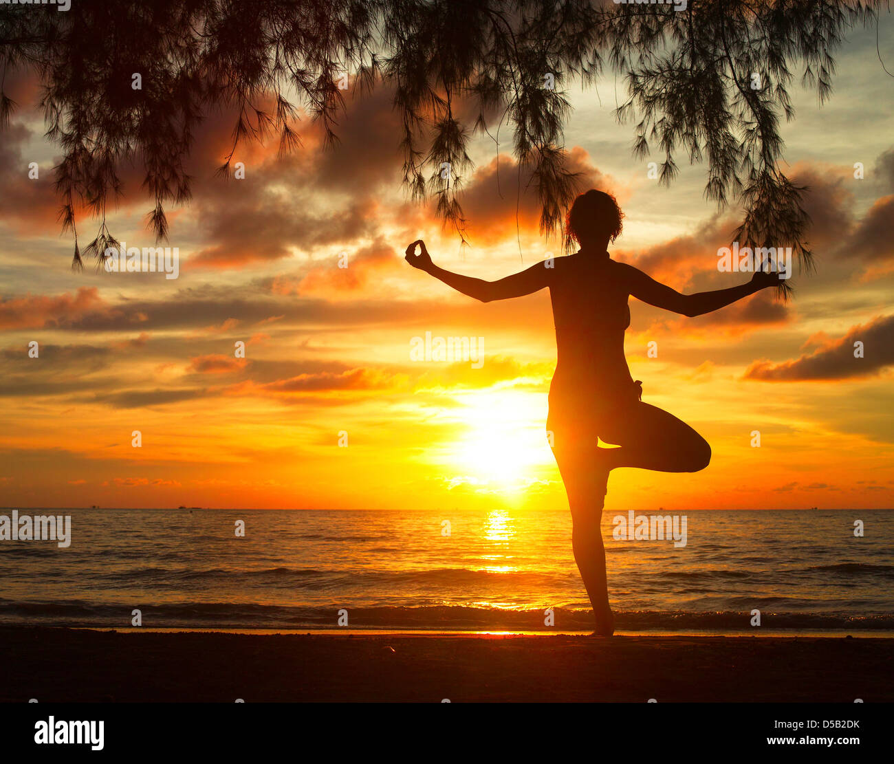 Giovane donna a praticare yoga sulla spiaggia nel Golfo del Siam (Thailandia) durante il tramonto. Foto Stock