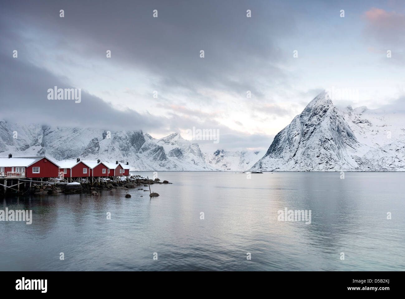 Una vista Reinefjorden verso la montagna di Olstind dal molo Hamnoy Harbour per le isole Lofoten in Norvegia Foto Stock