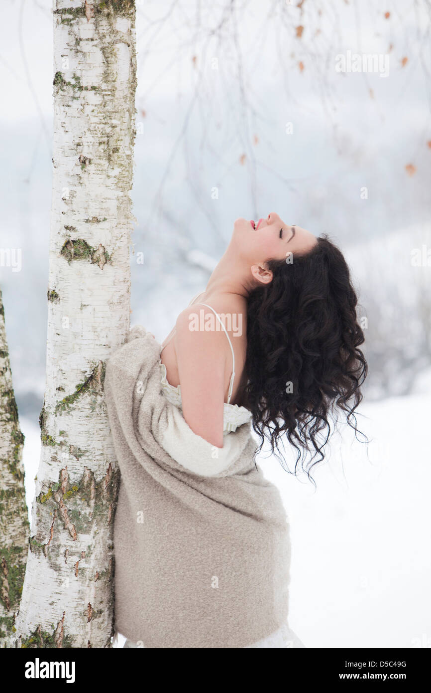 Donna appoggiata contro un albero con coperta Foto Stock