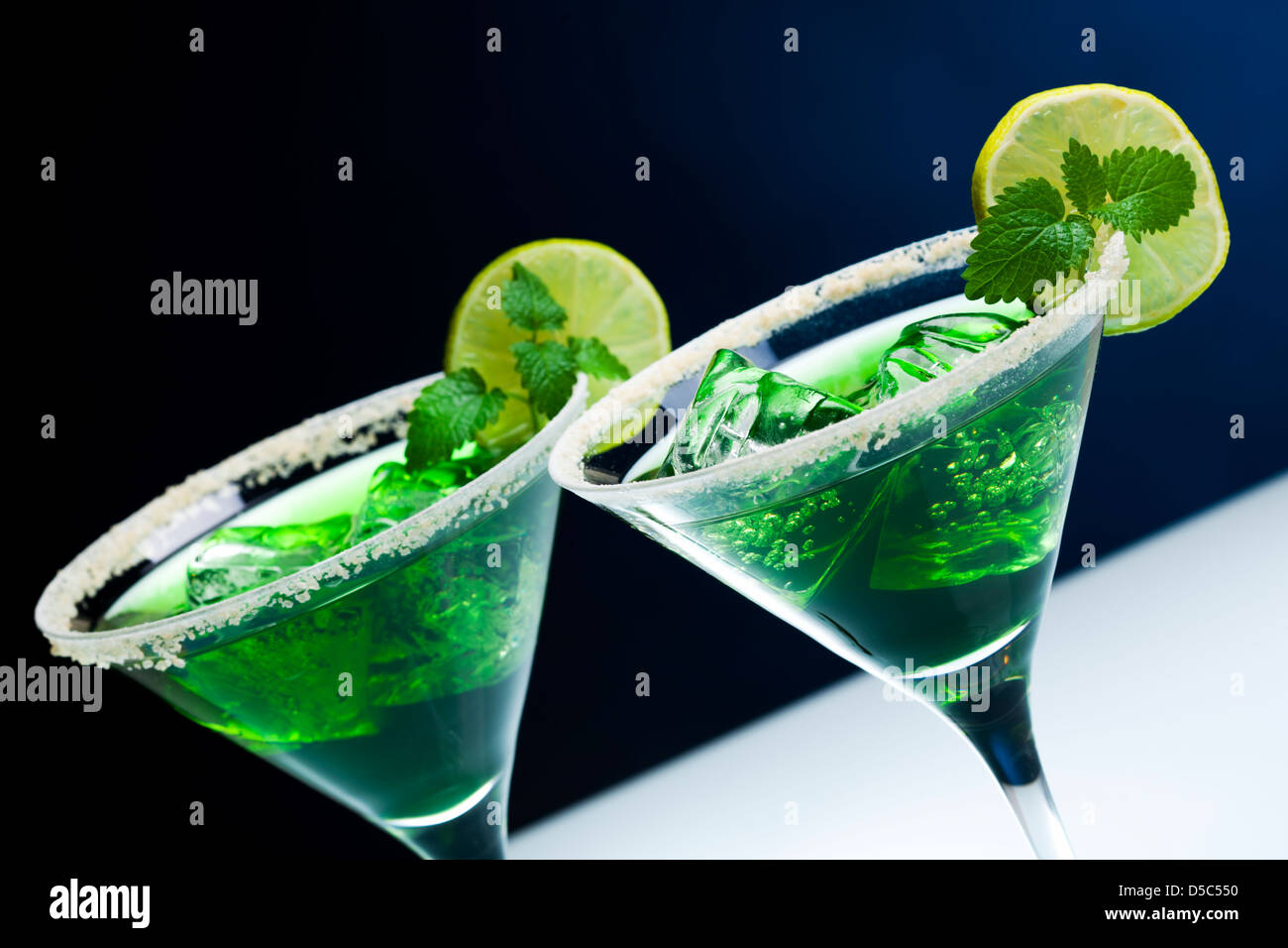 Green cocktail in bicchieri da martini con bordi zuccherato, lime slice di cubetti di ghiaccio, foglia di menta Foto Stock