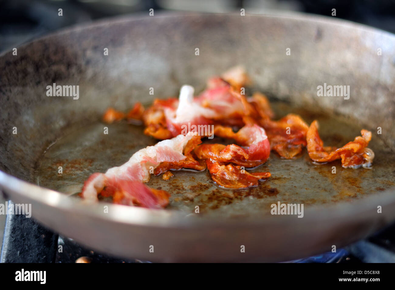 Pancetta fritta in una ghisa padella Foto Stock
