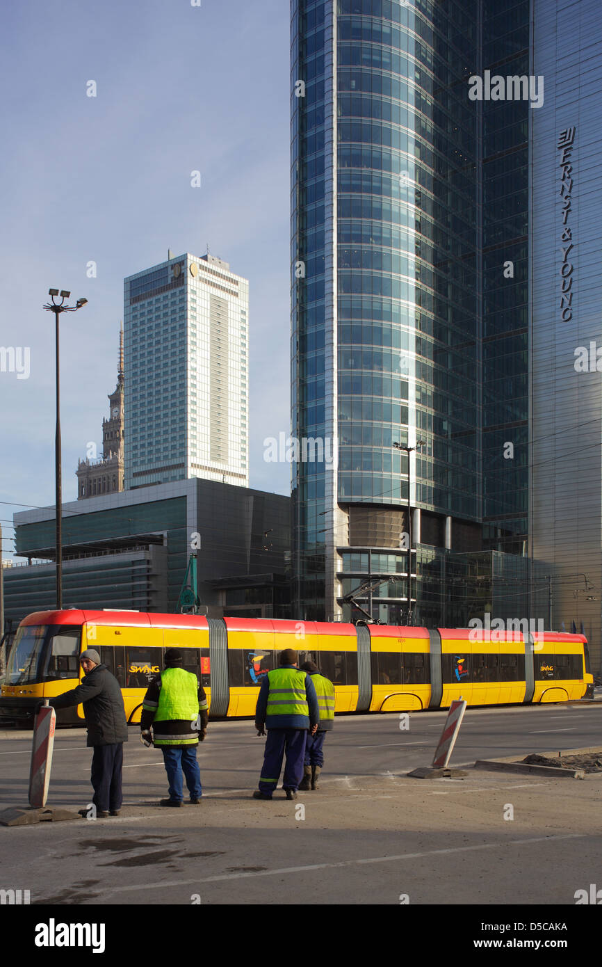 Varsavia, Polonia, lavorando con giubbotti di sicurezza e un tram davanti di grattacieli in centro città Foto Stock
