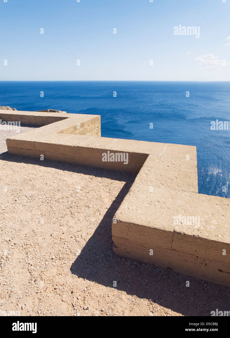 Basso muro di pietra con paesaggi marini. Il parapetto ha una forma a zig-zag e la foto è stata scattata in una giornata di sole Foto Stock