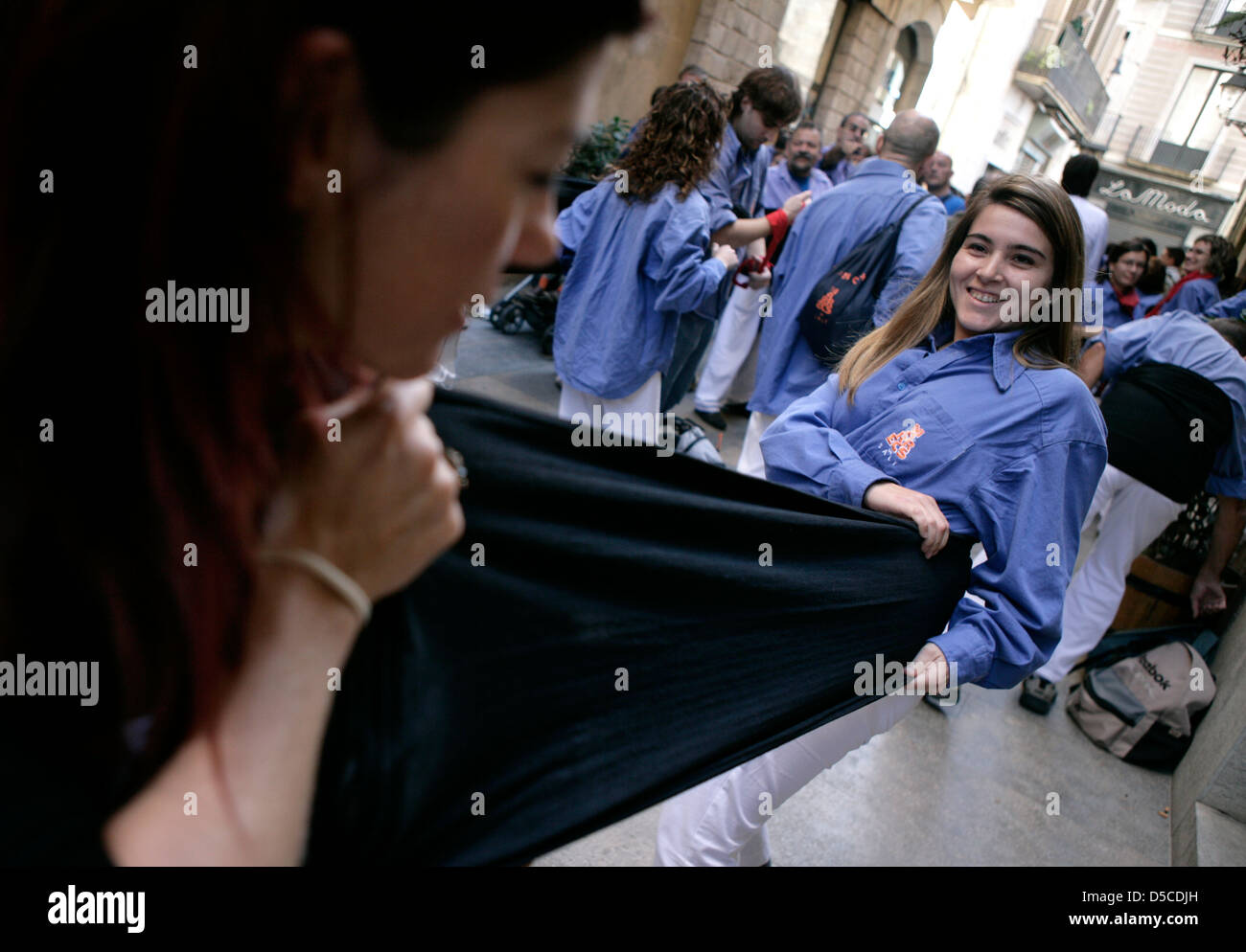 Casteller (Castello umano partecipante) tirando stretta la anta che viene utilizzato per legare e rafforzare la vita Foto Stock