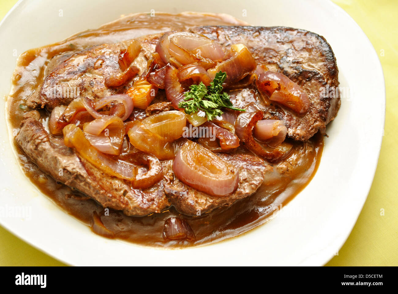 Fegato e cipolle su una piastra di sugo di carne Foto Stock
