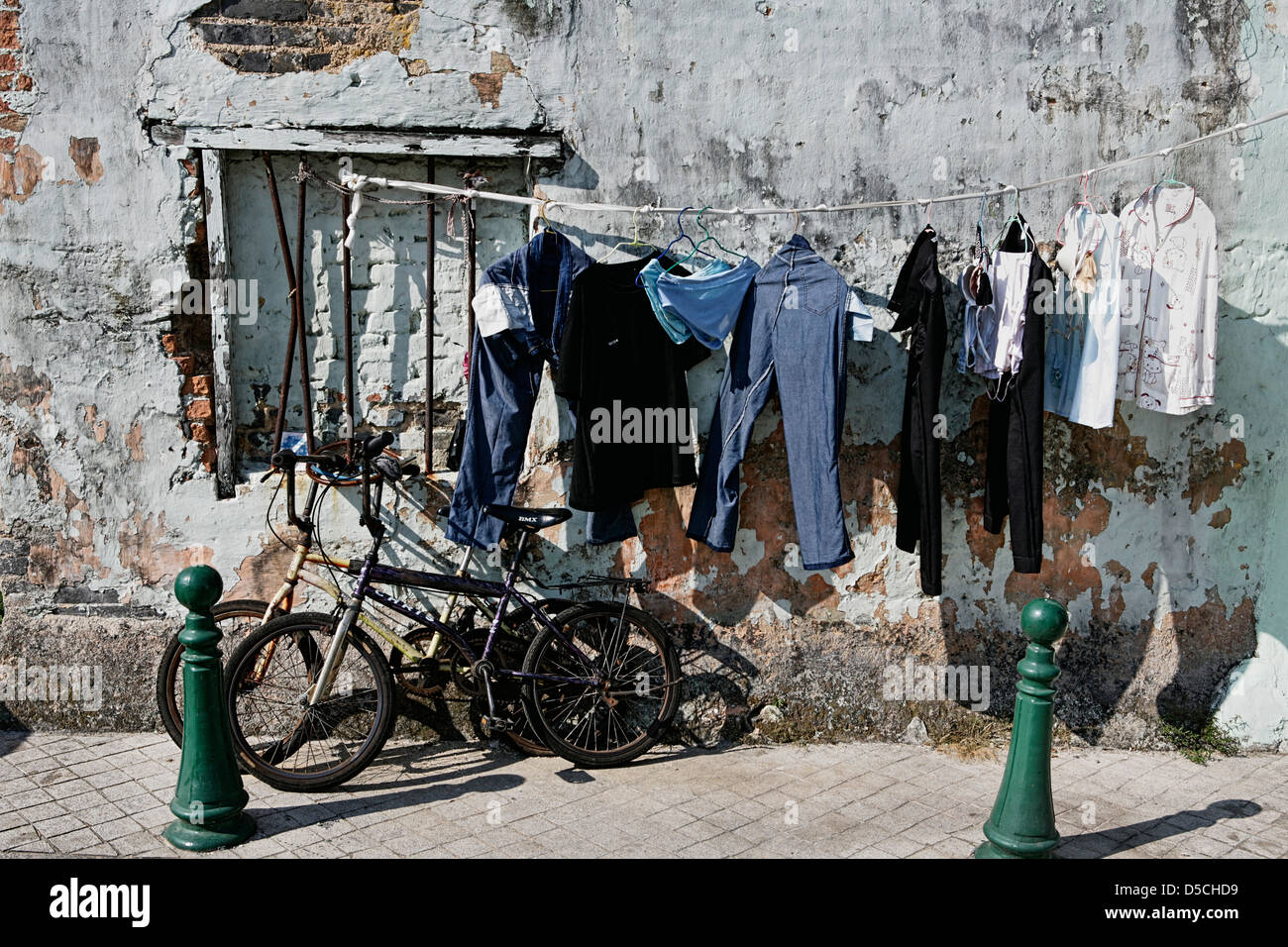 Biancheria stesa ad asciugare accanto alle biciclette in una strada a Macau Foto Stock