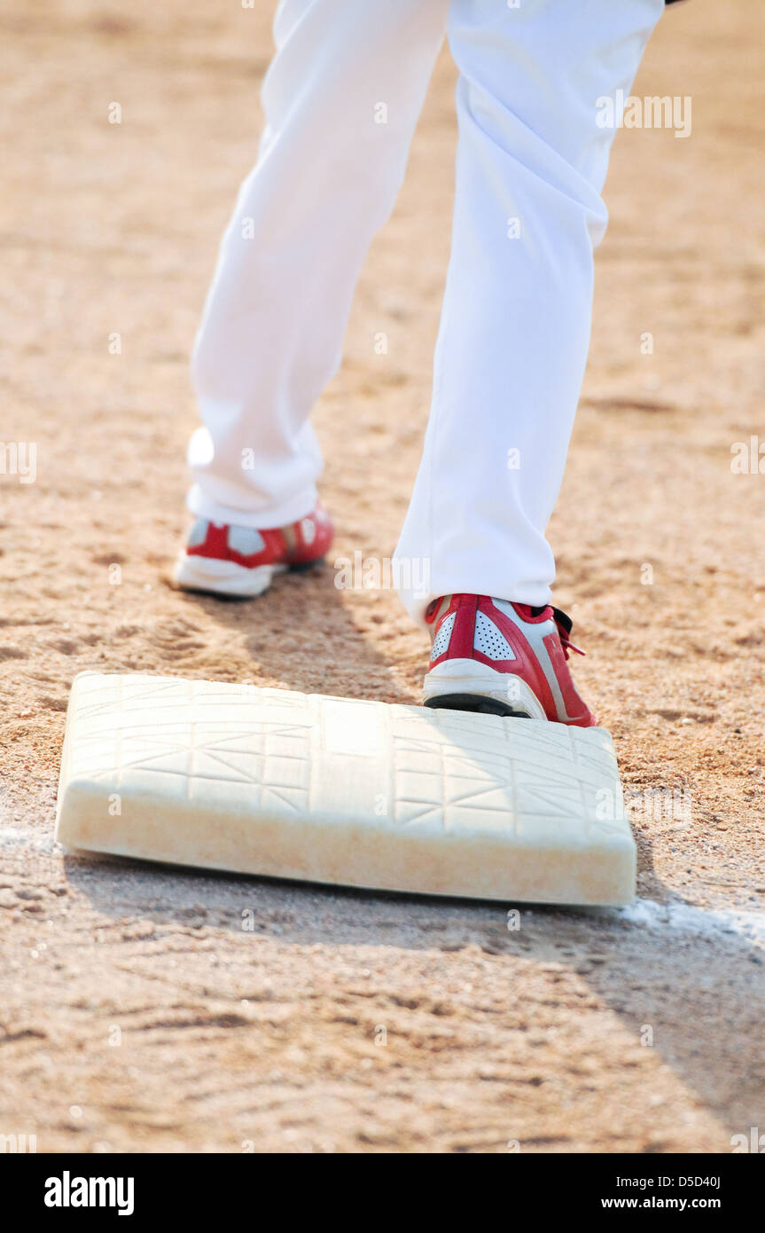 La parte inferiore del corpo colpo di baseball boy in piedi su una base. Foto Stock