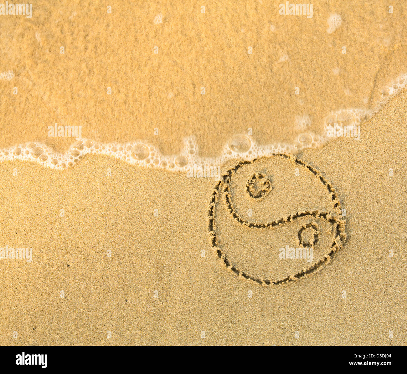 Yin Yang - simbolo scritto nella sabbia sulla spiaggia - soft onda di mare Foto Stock