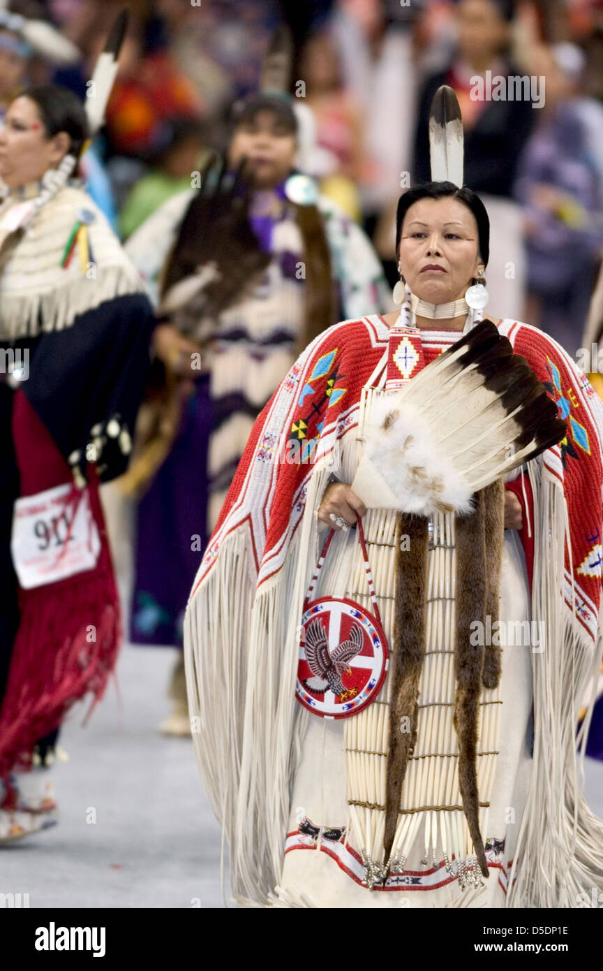 Questa fotografia a colori cattura una donna nativa americana che partecipa a una cerimonia Powwow. L'immagine mette in risalto il vibrante abito cerimoniale, le piume e l'importanza culturale dei poteri nelle tradizioni dei nativi americani. Foto Stock