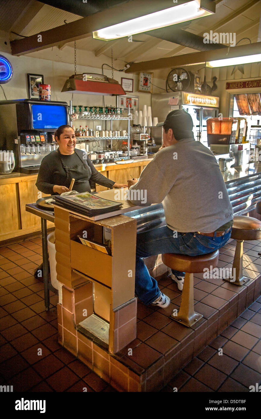 Un cliente in un ristorante messicano a Merced, CA, chat con il titolare mentre mangia il pranzo presso il contatore. Foto Stock