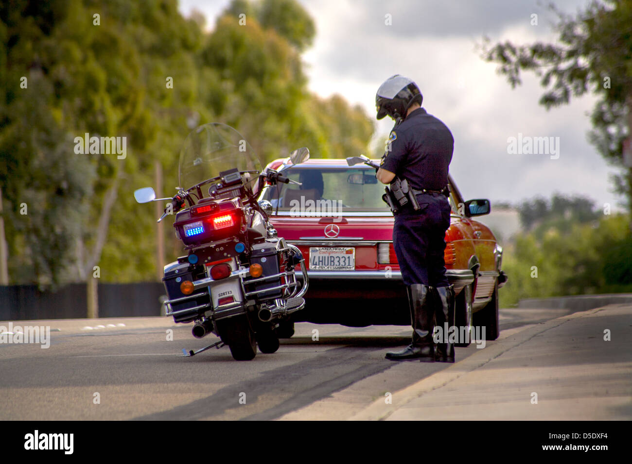 Un motociclo poliziotto scrive un biglietto a un arresto del traffico in arancione, CA. Foto Stock
