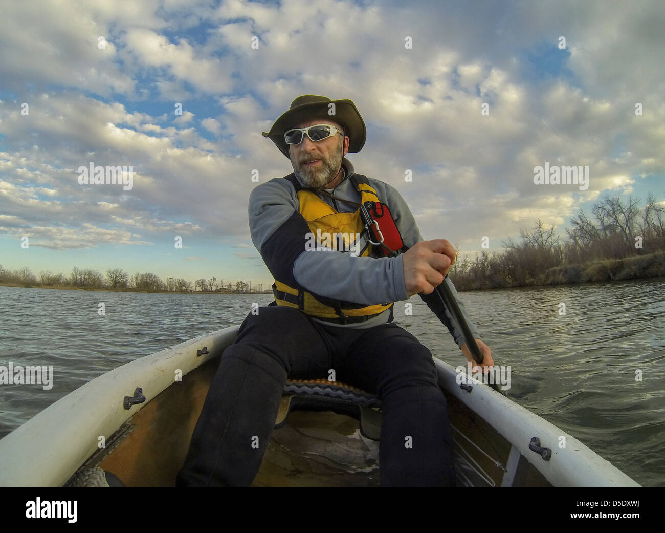 Maschio senior paddling una canoa sul lago calmo in primavera in Fort Collins, Colorado, POV shot da una barca a prua Foto Stock