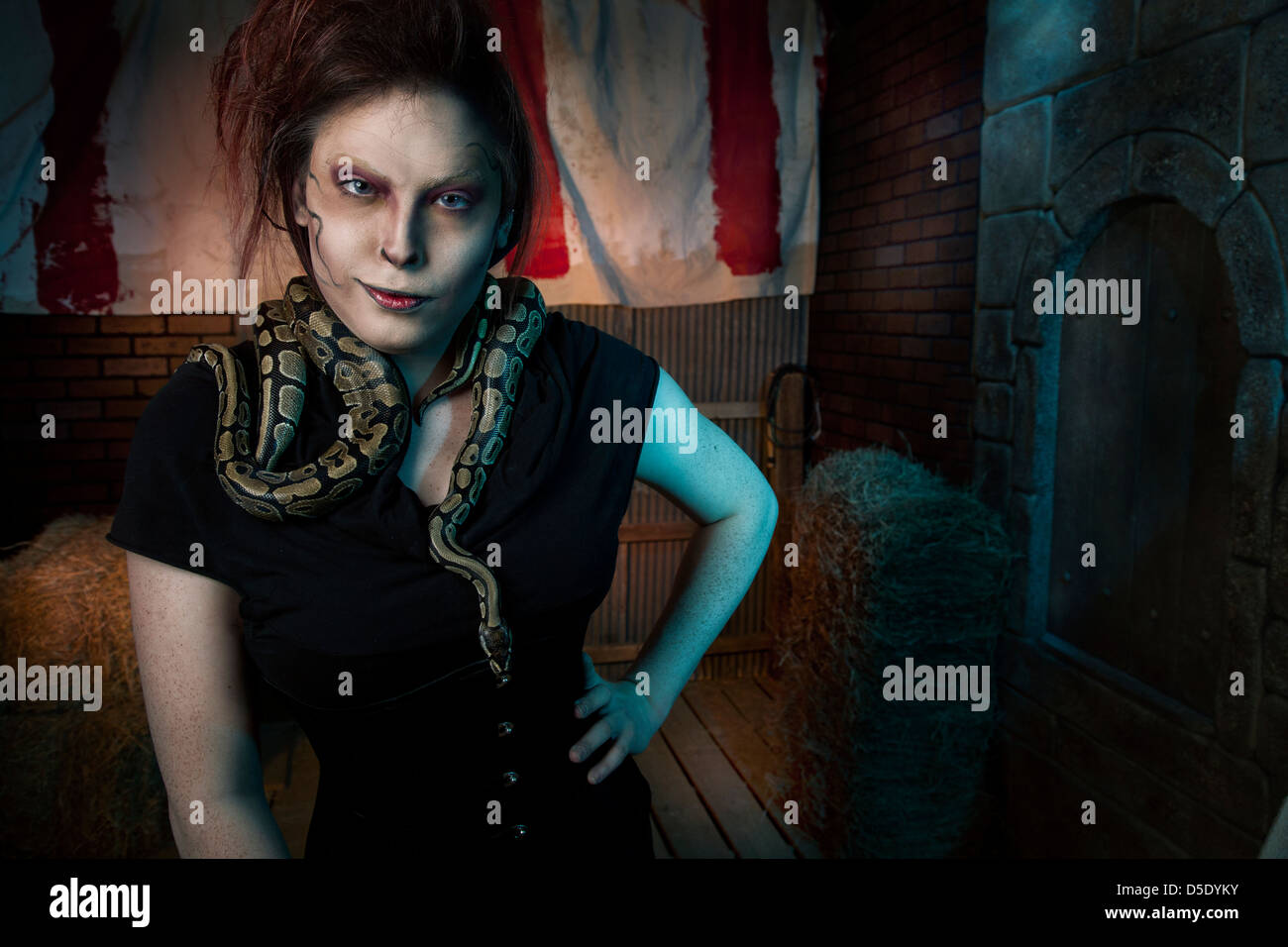 Donna con serpenti attorno al collo in tented vicolo buio Foto Stock