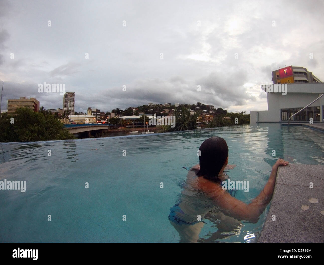 Donna in hotel Piscina che si affaccia Townsville in serata, Queensland, Australia. N. PR o MR Foto Stock