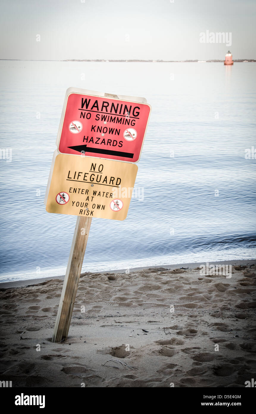 Cartelli di avvertimento sulla spiaggia di Sandy Point State Park, con la Secca faro in background Foto Stock