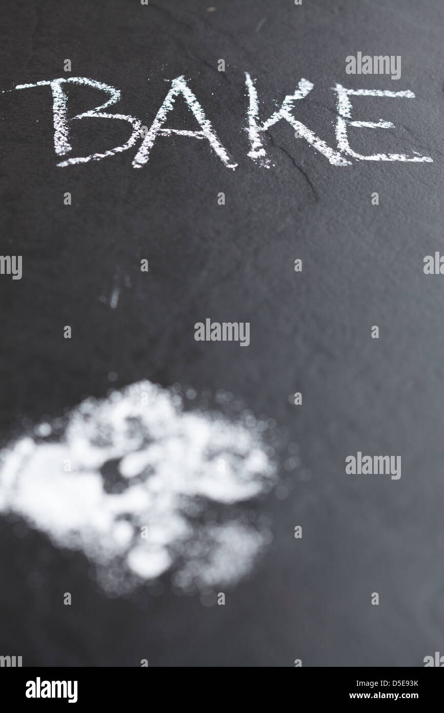 Primo piano dello sfondo scuro con zucchero a velo e cuocere la parola scritta in Chalk Foto Stock