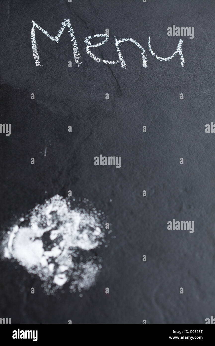 Primo piano dello sfondo scuro con zucchero a velo e menu di parola scritta in Chalk Foto Stock