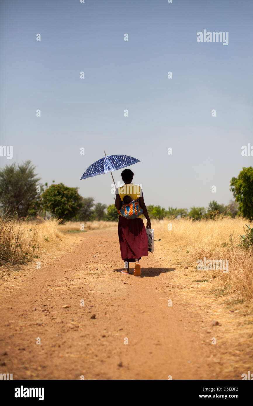 Una donna che porta un bambino sulla schiena vicino al villaggio di Nandom, nel nord del Ghana. Foto Stock