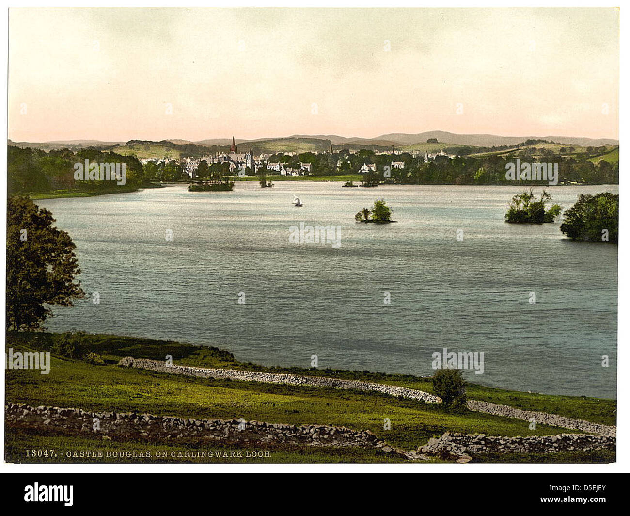 Una fotografia che mostra Carlingwark Loch vicino a Castle Douglas, Scozia. L'immagine evidenzia la bellezza serena del lago e delle colline circostanti, con un'isola visibile in lontananza. Foto Stock