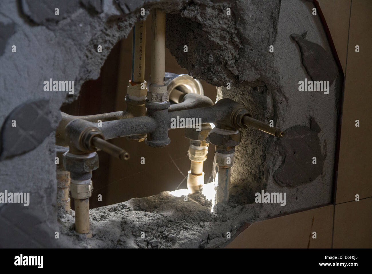 Rotture di muro di calcestruzzo di recupero rivelando plumbing interna Foto Stock