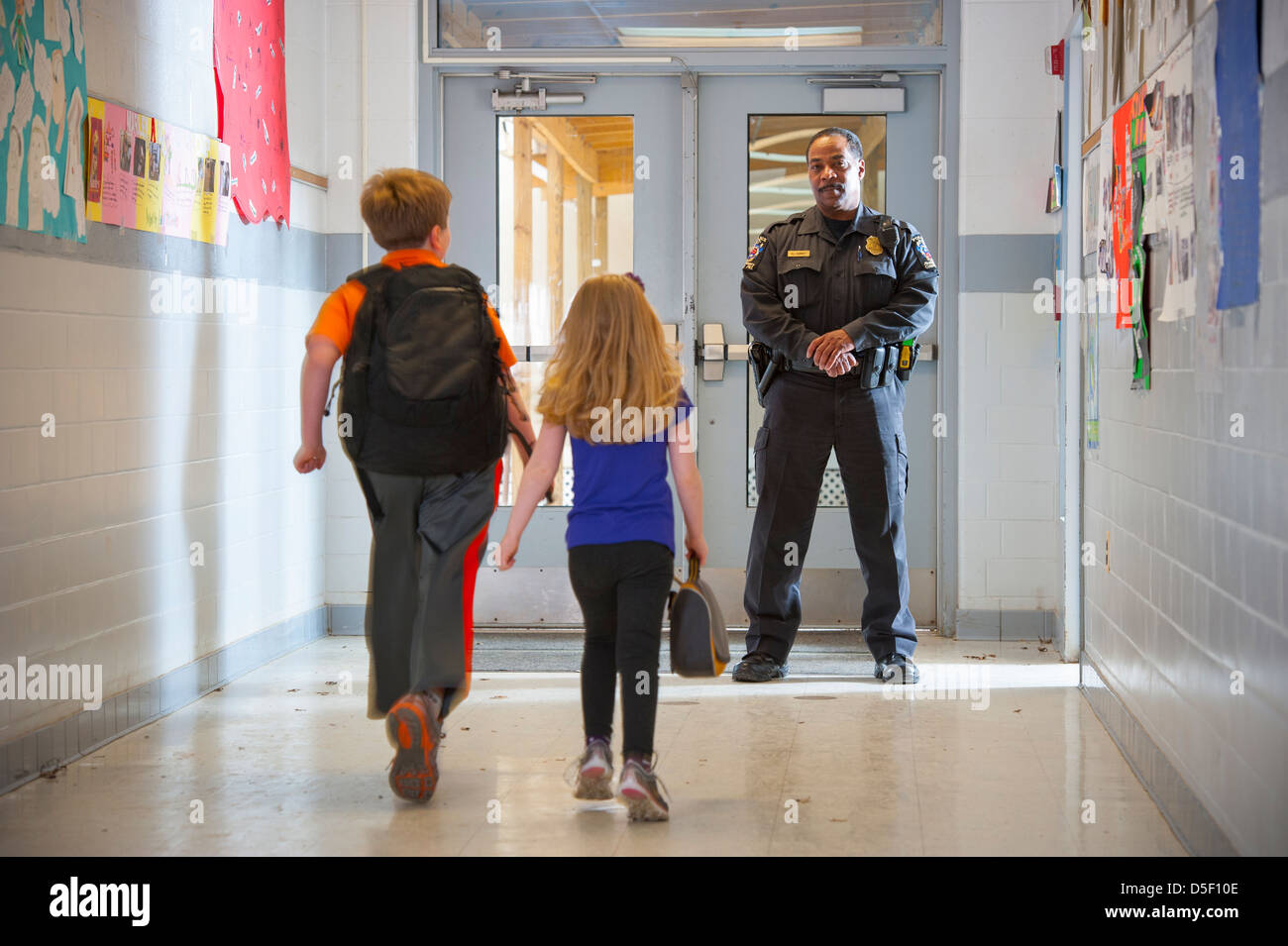 USA la sicurezza nelle scuole pubbliche funzionario di polizia con un ragazzo e una ragazza in school hall Foto Stock